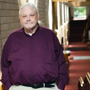 Bill Warfield standing for his portrait in Zoellner Arts Center atrium.