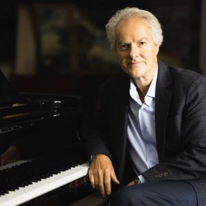 Eugene Albulescu posing at a piano for his portrait.