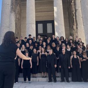Members of the Lehigh University Choral Arts perform outside in front of a building with large stone pillars.