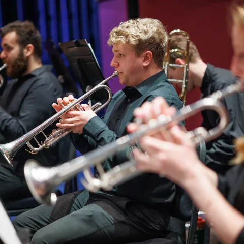 Symphonic band members playing the trumpet. 