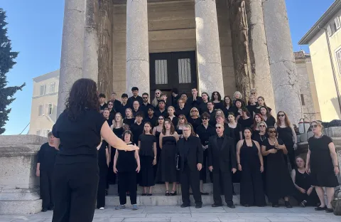 Members of the Lehigh University Choral Arts perform outside in front of a building with large stone pillars.