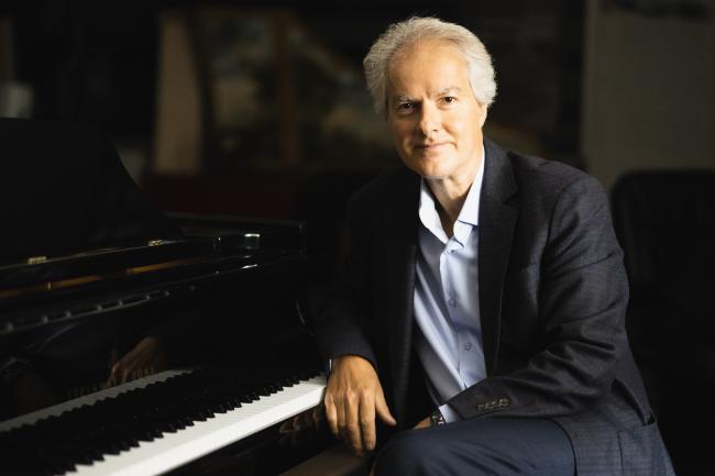 Eugene Albulescu posing at a piano for his portrait.