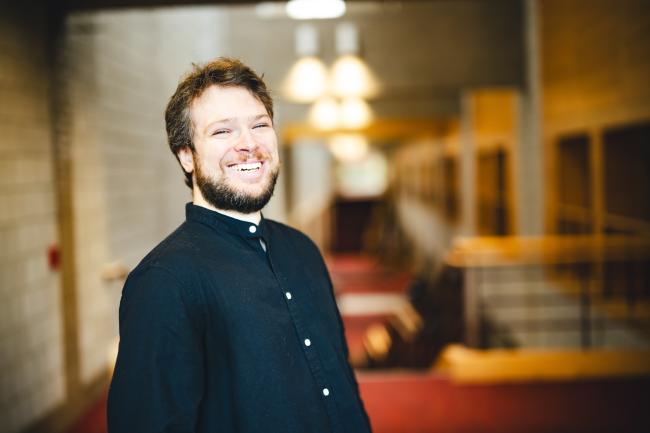 Joshua Aguiar standign for his portrait in the Zoellner Arts Center atrium.