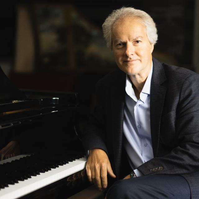 Eugene Albulescu posing at a piano for his portrait.
