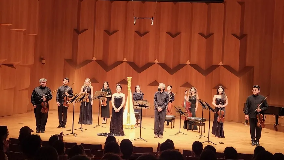 Musicians standing with their instruments on stage for a concert of music by Earl Kim at the Seoul Arts Center, Korea coached and introduced by Paul Salerni.