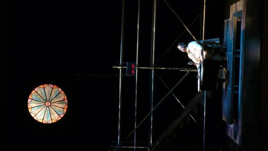 Performer sitting at a table with a microphone wearing headphones listening to music.