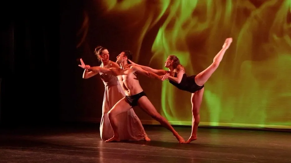 Trio of dancers from "Haunted" performing on stage with a backdrop of fire.
