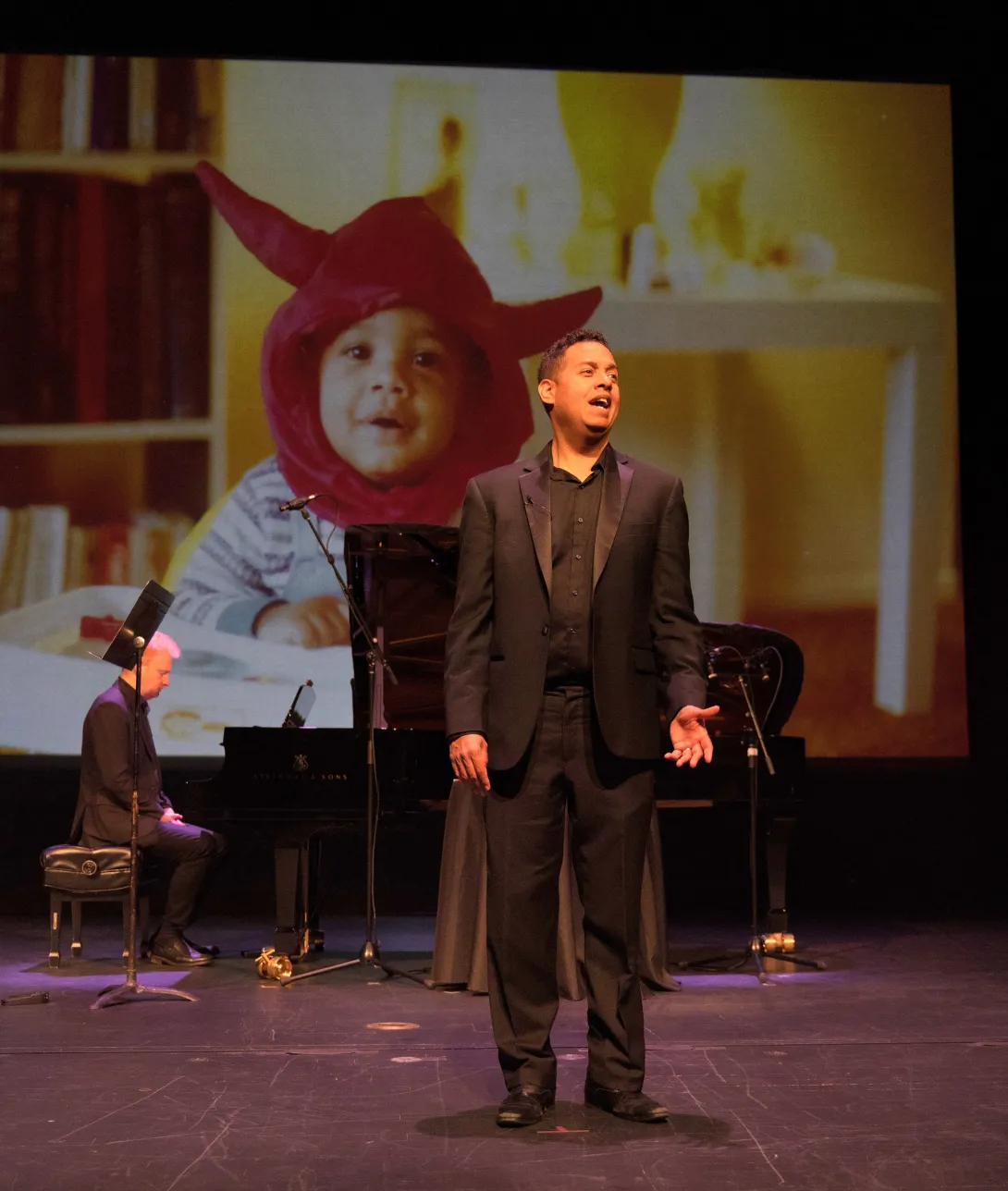 Michael Jorgensen on stage with his baby photo as the backdrop.