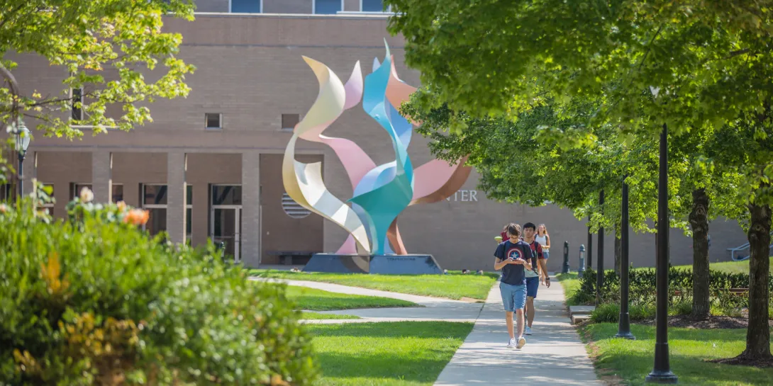 Student walking along the path in front of Zoellner Arts Center.
