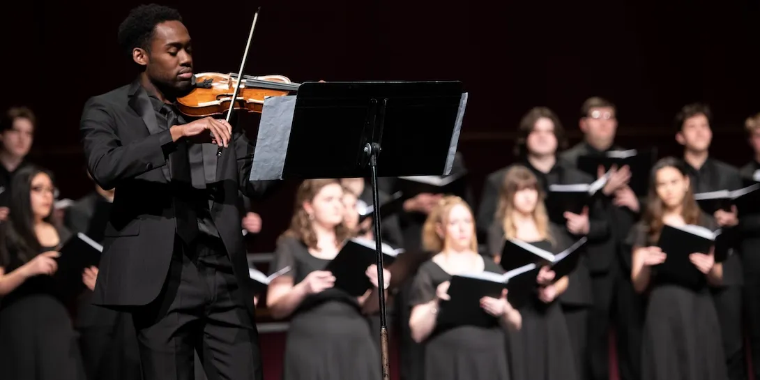Violinist playing with members of a choir.